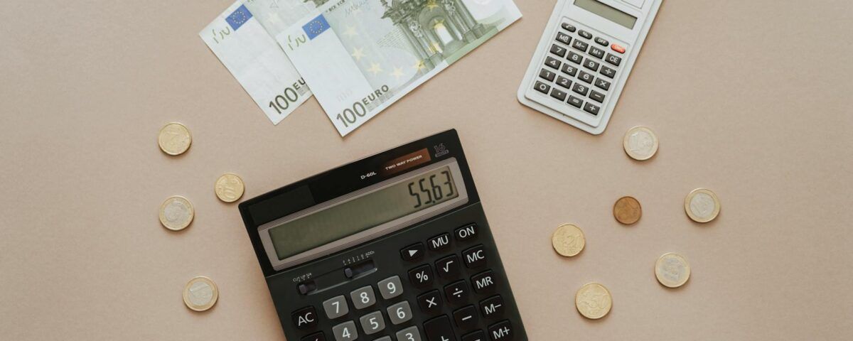 black and silver calculator beside silver coins