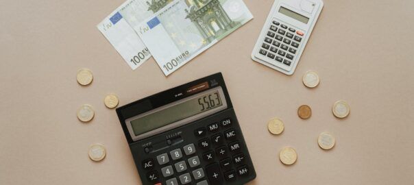 black and silver calculator beside silver coins