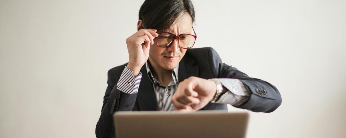 confused businessman checking time on wristwatch